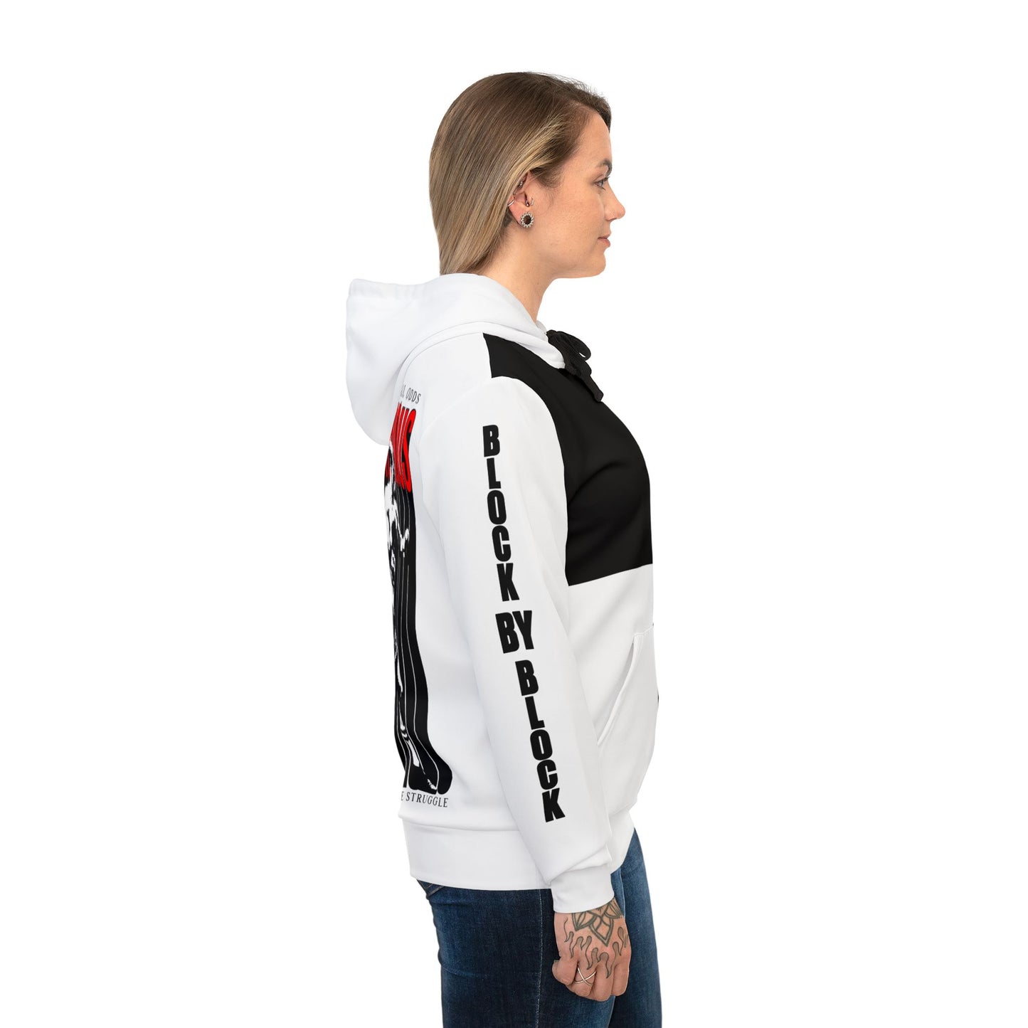 Side view of a female model wearing the black and white split hoodie. The sleeve prominently displays the bold text 'Block by Block' with red details on the back for an edgy, urban look.