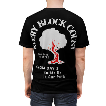 Rear view of a model wearing the Every Block Count black t-shirt featuring a red and white tree graphic and motivational text.