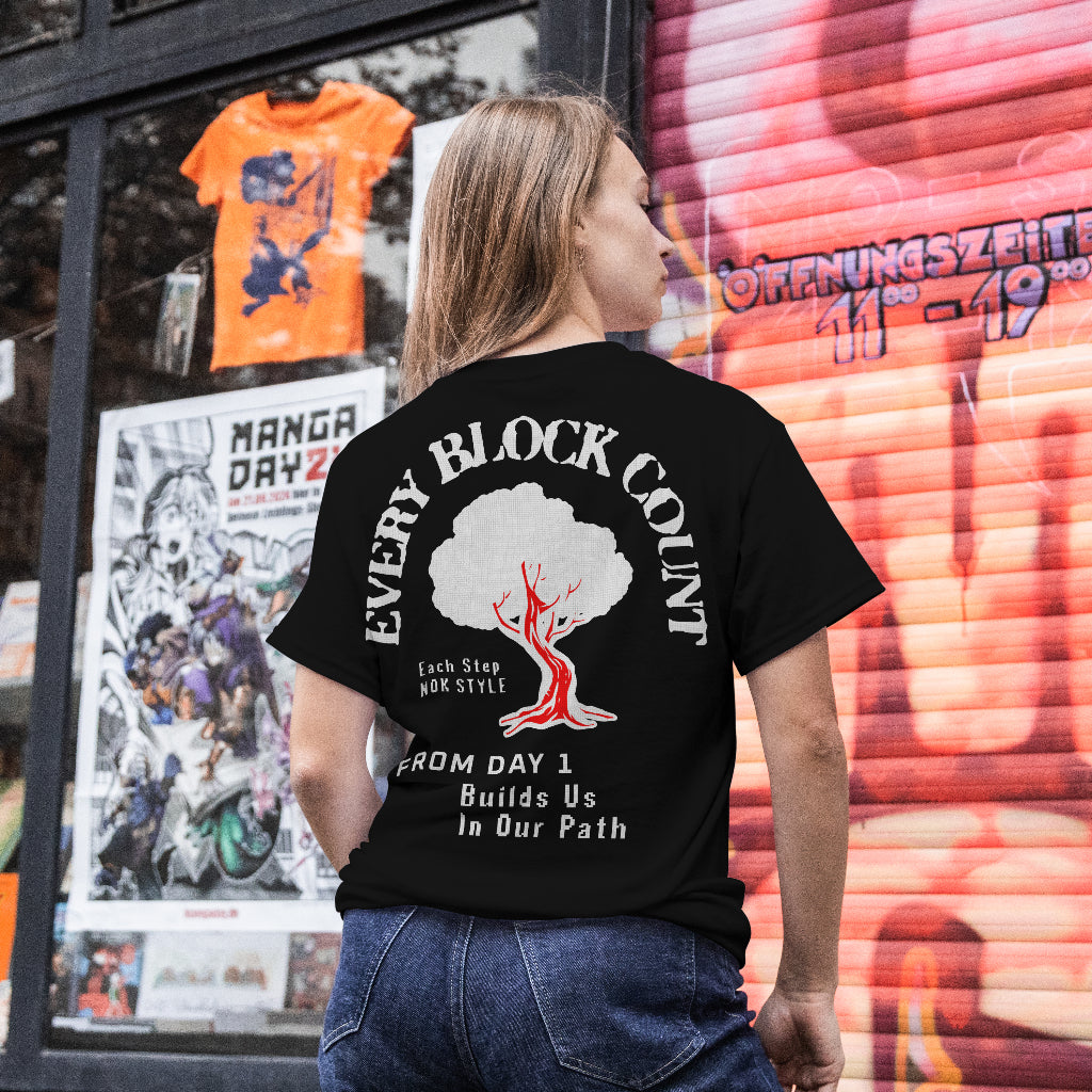 Model wearing the Every Block Count black t-shirt in an urban setting with bold rear graphic and motivational text.