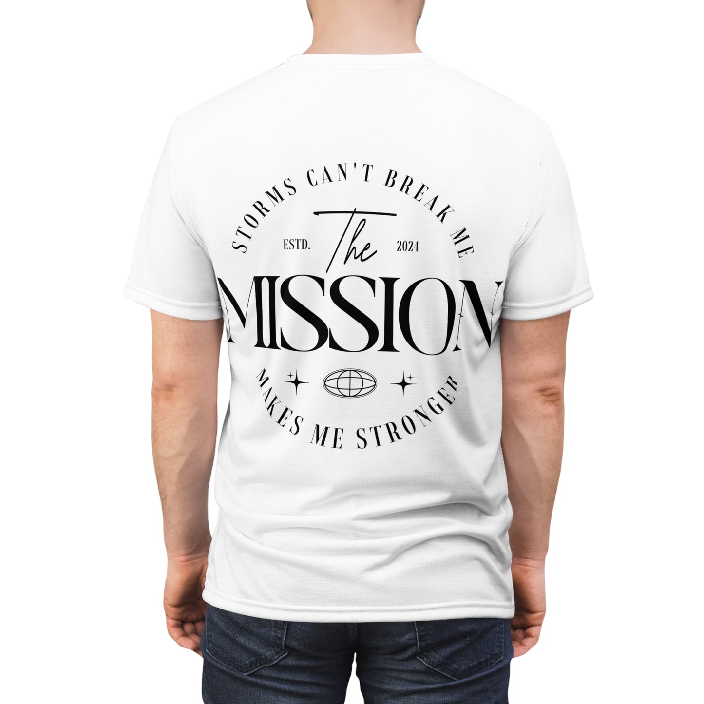 Back view of a white T-shirt modeled by a person, featuring the text 'Storms Can’t Break Me. Makes Me Stronger. The Mission' in elegant typography.