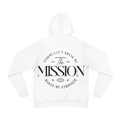 Flat lay of a white hoodie with bold typography on the back reading 'Storms Can’t Break Me. Makes Me Stronger. The Mission.