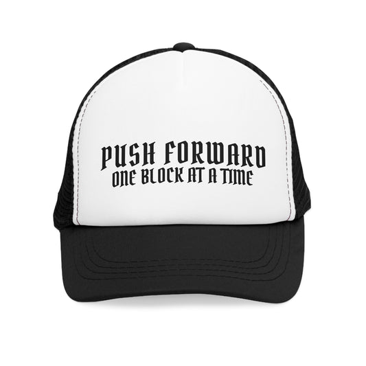 Front view of the black and white trucker cap with bold text 'Push Forward, One Block at a Time' displayed prominently on the white crown.