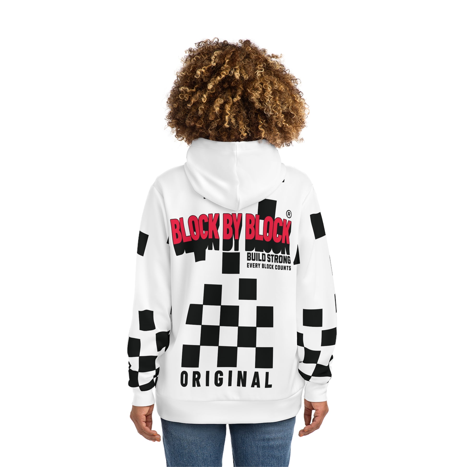 Back view of a woman wearing a white hoodie showcasing 'Block by Block' text in red and a bold black checkered design.
